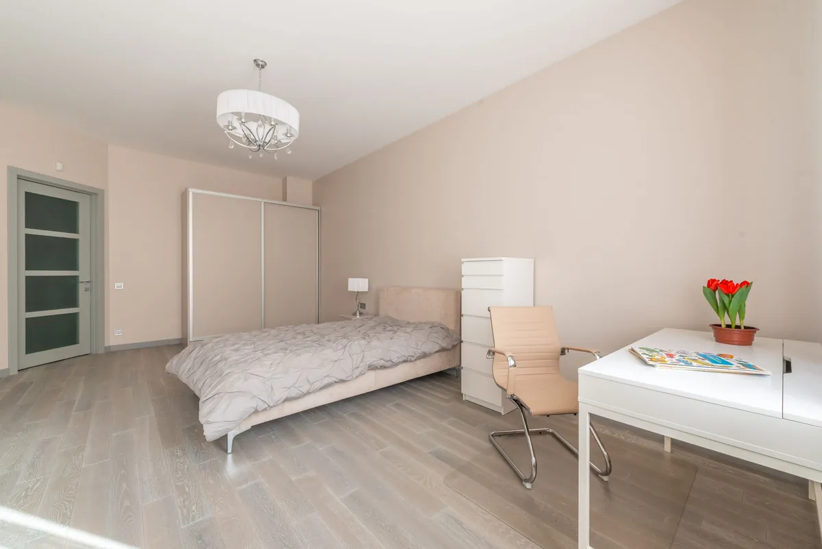 Bedroom with a made bed and a white desk