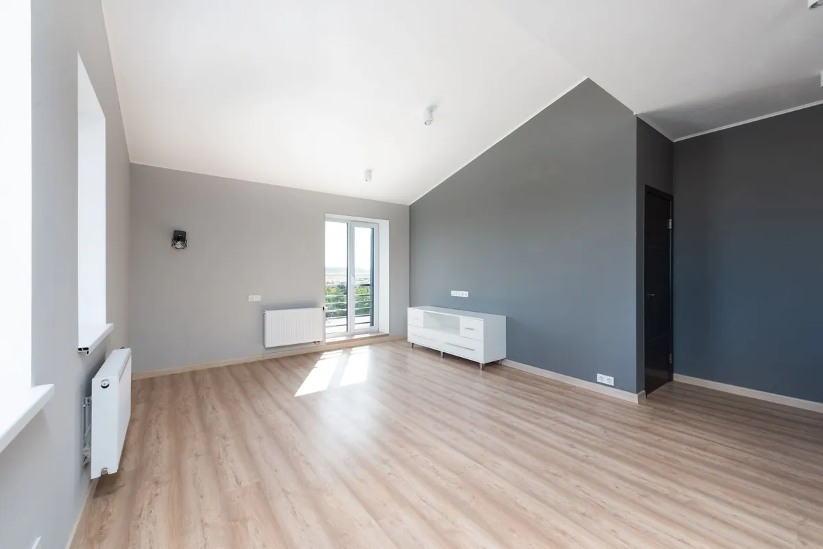 Empty apartment room with light floors and a balcony door