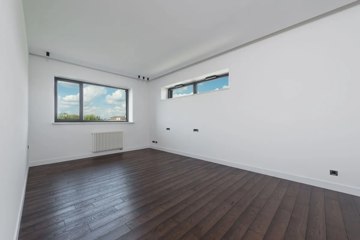 Empty room with dark wood floors and wide windows