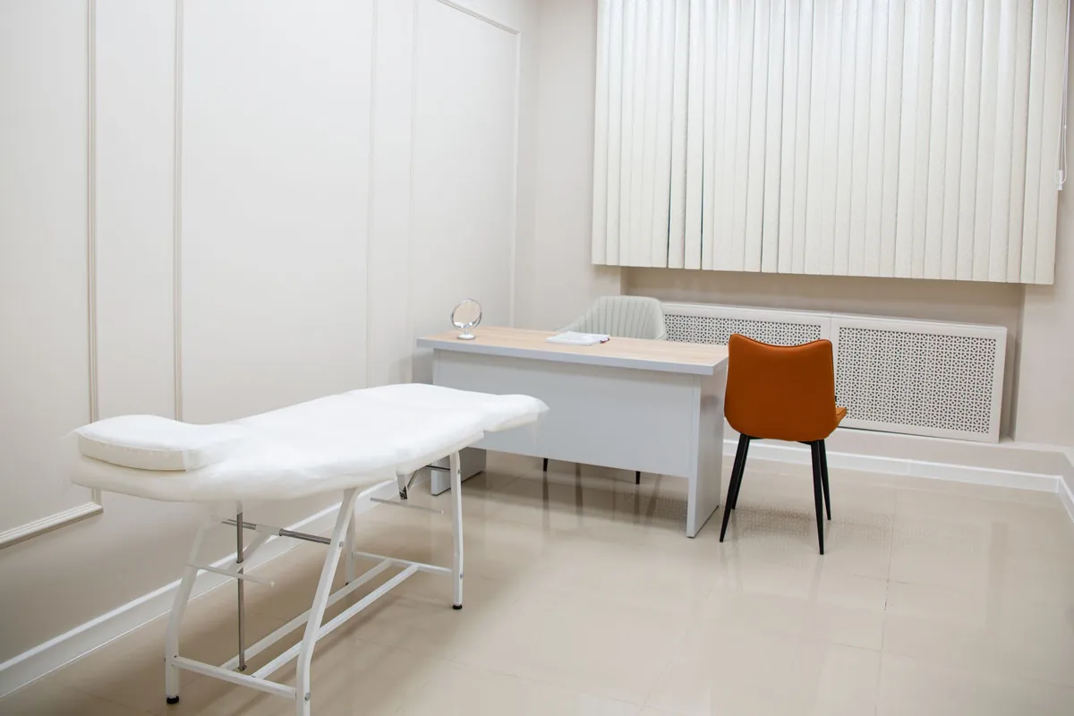 Exam room with a white treatment table and an orange chair