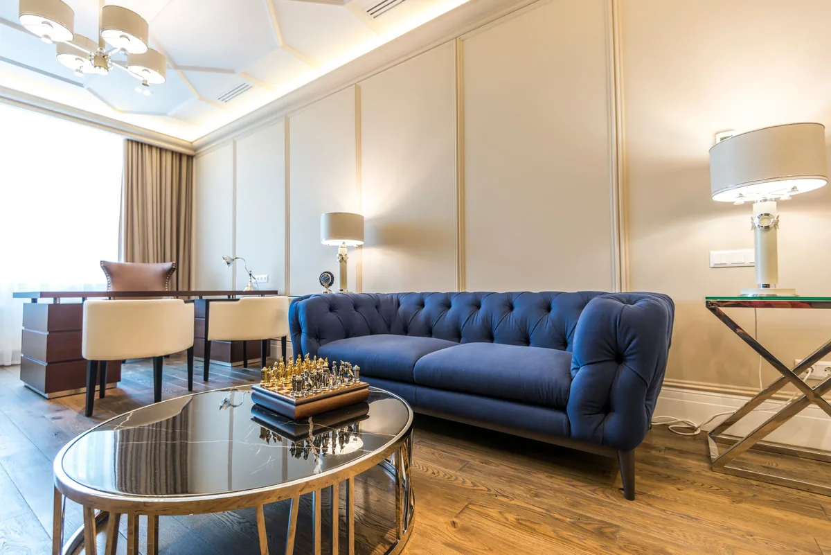 Sitting room with a blue tufted sofa and a round glass table