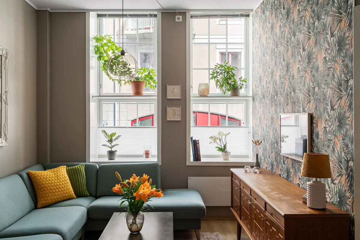Living room with a green sofa, plants and tall windows