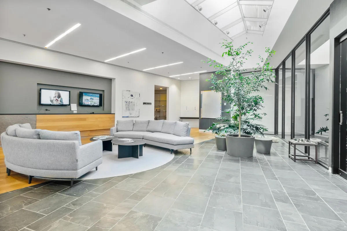 Bright lobby with gray sofas, a potted tree and a tile floor