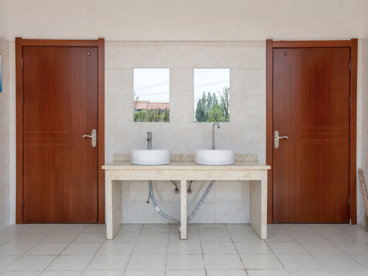Restroom with twin sinks between two wood doors
