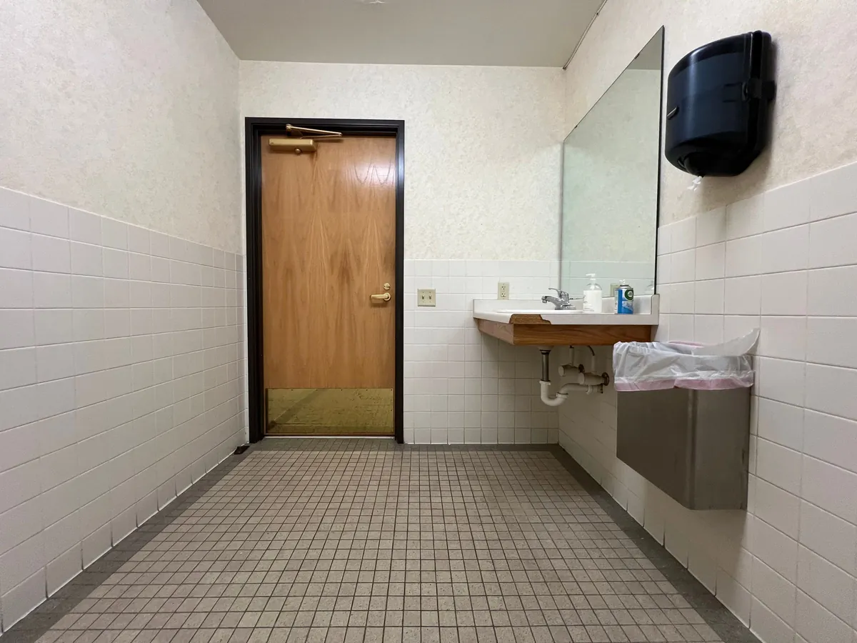 Tiled public restroom with a sink and a towel dispenser