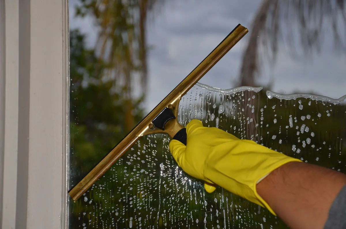 A squeegee clearing soapy water from a window
